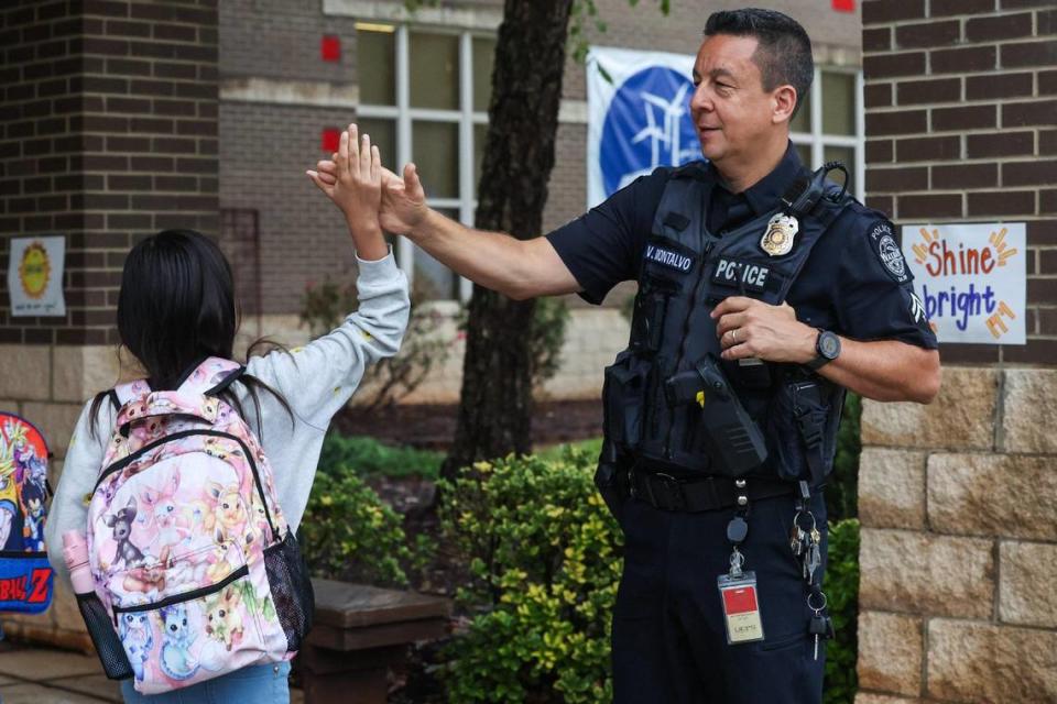 School resource officer Victor Montalvo, right, greets a student with a high-five as students arrive for the first day of school at Waxhaw Elementary School on Monday, August 28, 2023.