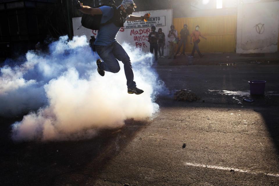 A demonstrator jumps over tear gas launched by Bolivarian National Guards during clashes in Caracas, Venezuela, Sunday, March 2, 2014. Since mid-February, anti-government activists have been protesting high inflation, shortages of food stuffs and medicine, and violent crime in a nation with the world's largest proven oil reserves. (AP Photo/Rodrigo Abd)