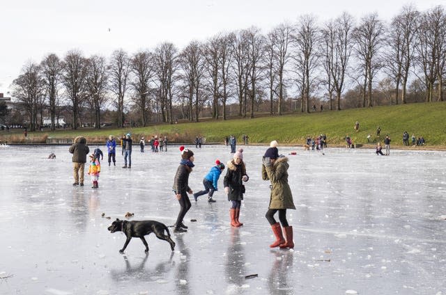 People walk their dogs across the frozen pond in Inverleith Park, Edinburgh