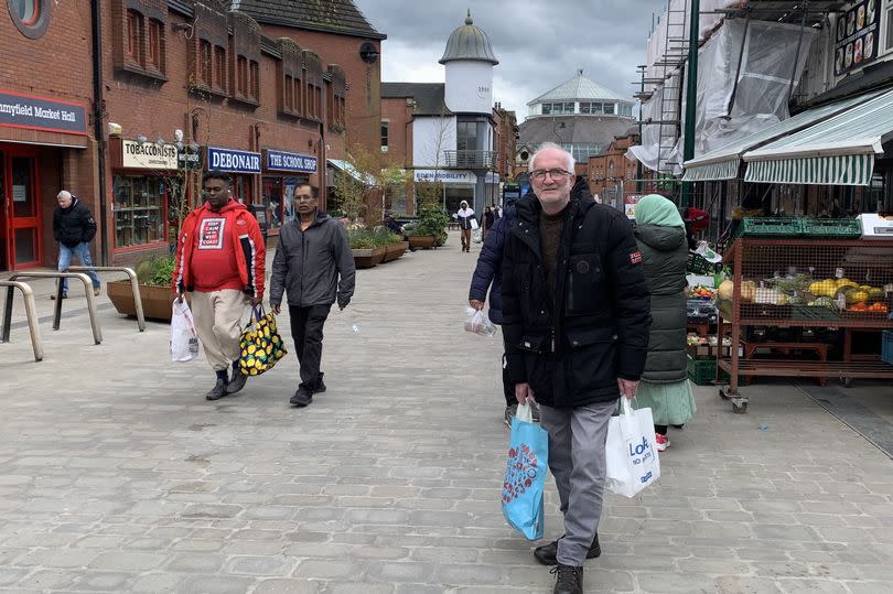 A man in his sixties or seventies holding shopping bags.
