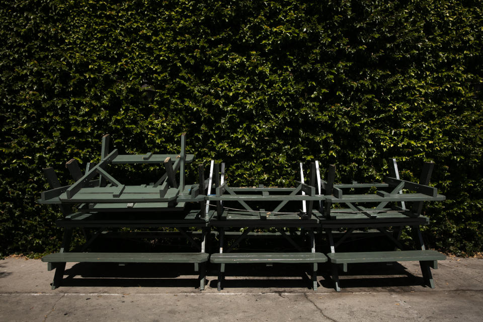 Picnic tables and benches are stacked up against a wall outside a bar temporarily closed due to the coronavirus pandemic, Wednesday, July 8, 2020, in Los Angeles. (AP Photo/Jae C. Hong)