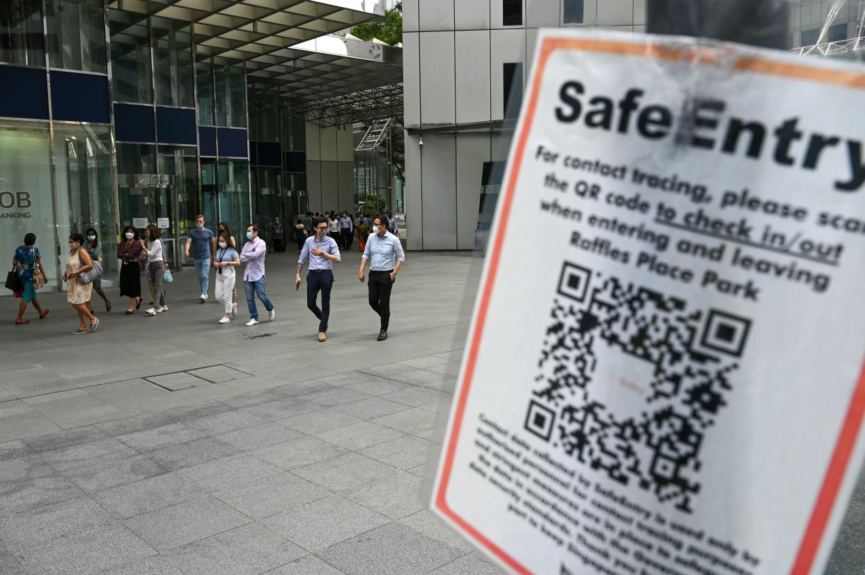 A Covid-19 coronavirus contact tracing sign is pictured as people walk out during lunch break at the Raffles Place financial business district in Singapore on September 14, 2021. (Photo by Roslan RAHMAN / AFP) (Photo by ROSLAN RAHMAN/AFP via Getty Images)