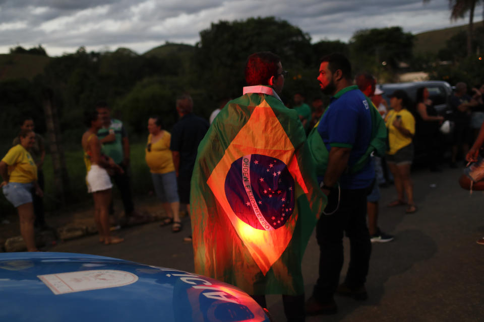 Supporters of former lawmaker Roberto Jefferson stand near his house in Levy Gasparian, Rio de Janeiro state, Brazil, Sunday, Oct. 23, 2022. Jefferson, an ally of Brazilian President Jair Bolsonaro, fired gunshots and a grenade at federal policemen who tried to arrest him in for insulting supreme court ministers, according to Brazil’s federal police. (AP Photo/Bruna Prado)