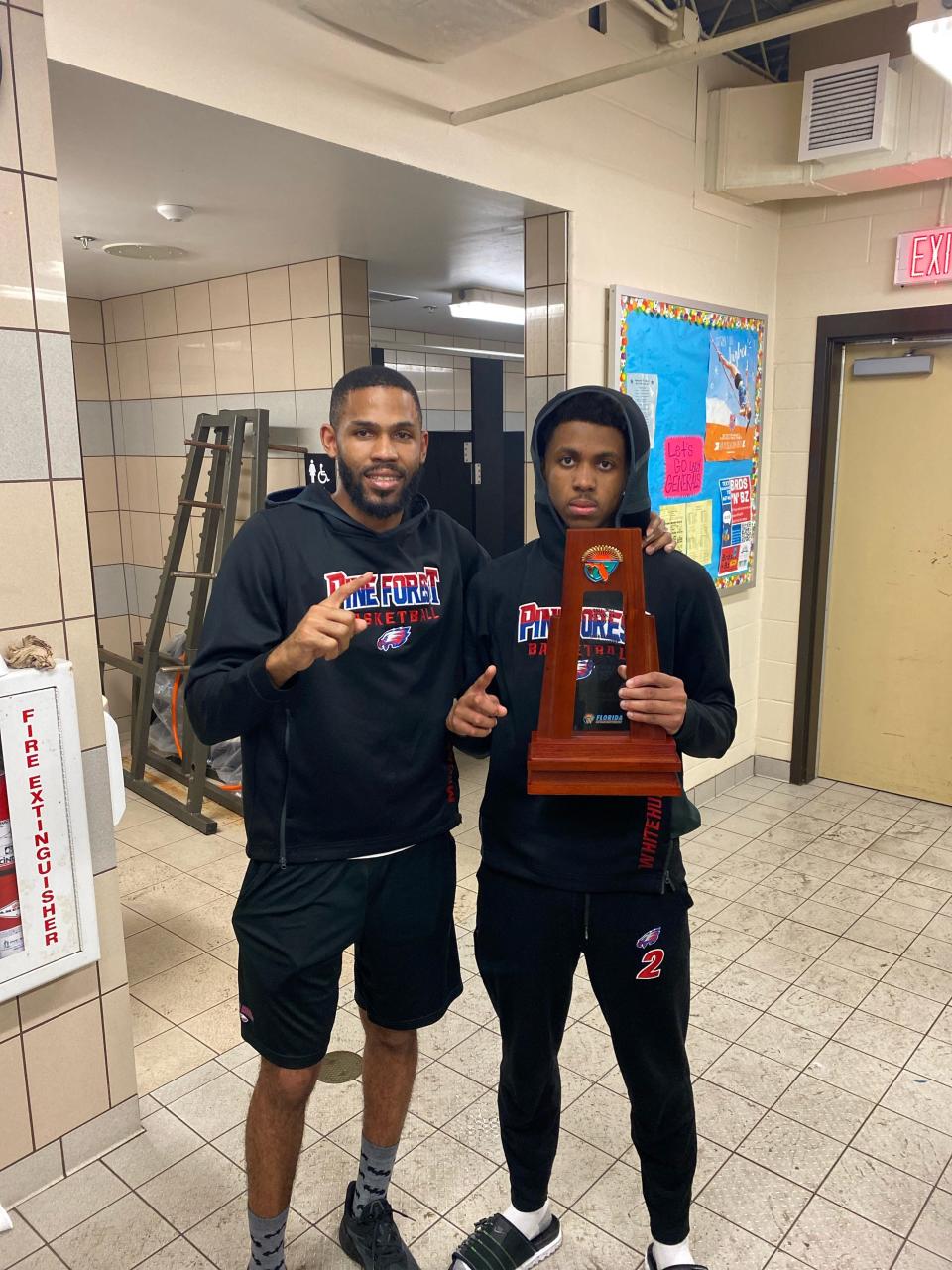Pine Forest head coach Ty McCants and junior guard Joshua Whitehurst pose with the Region 1-5A trophy after defeating Jacksonville Ridgeview 62-59 on Friday, Feb. 25, 2022 from Orange Park.