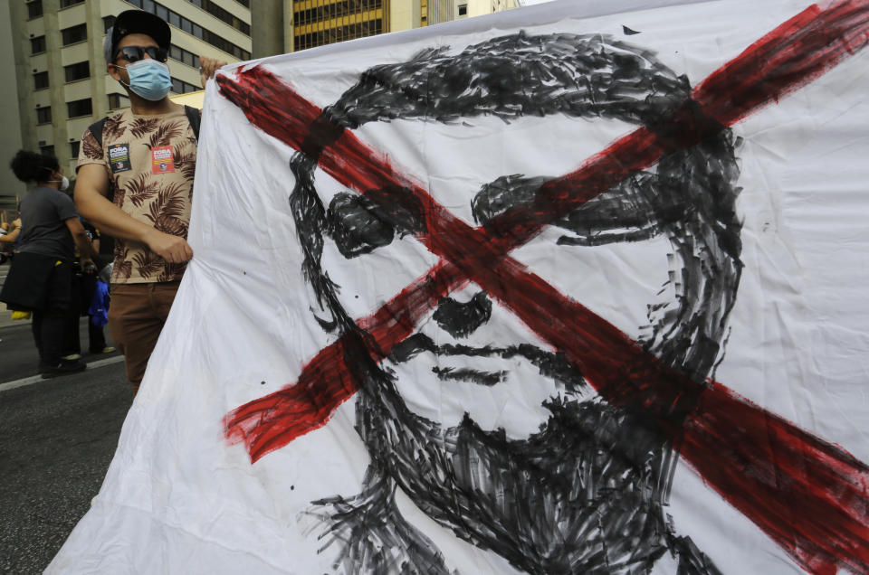 A demonstrator holds a banner with an x crossed over an image of Brazilian President Jair Bolsonaro, during a protest demanding Bolsonaro resign, in Sao Paulo, Brazil, Saturday, July 3, 2021. Activists called for nationwide demonstrations against Bolsonaro, gathering protestors to demand his impeachment amid allegations of potential corruption in the Health Ministry’s purchase of COVID-19 vaccines. (AP Photo/Nelson Antoine)