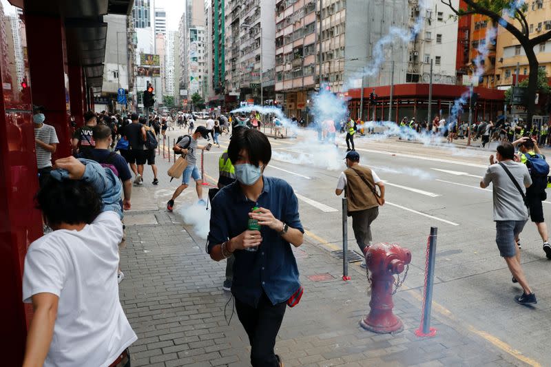 Anti-government protesters react as riot police fire tear gas to disperse them during a march against Beijing's plans to impose national security legislation in Hong Kong