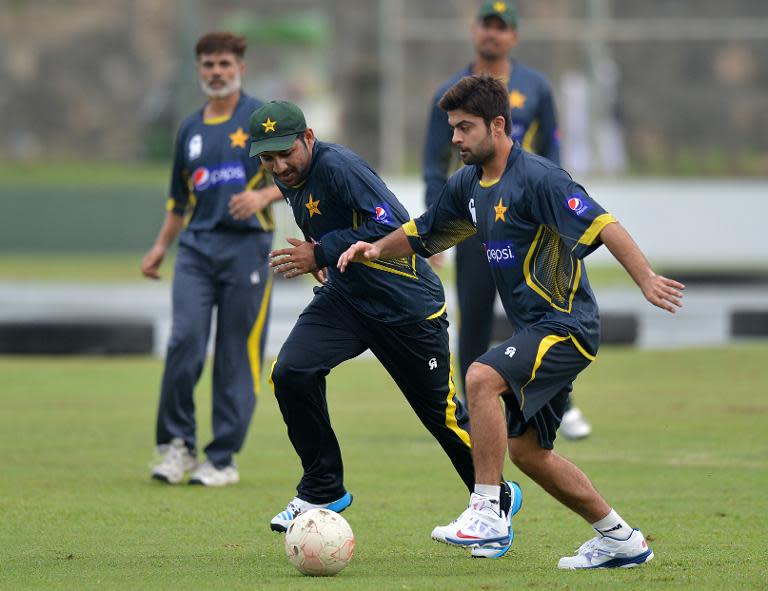 Pakistan cricketer Sarfraz Ahmed (2nd L) and teammate Ahmed Shehzad (R) play football during team training session in Galle on August 3, 2014