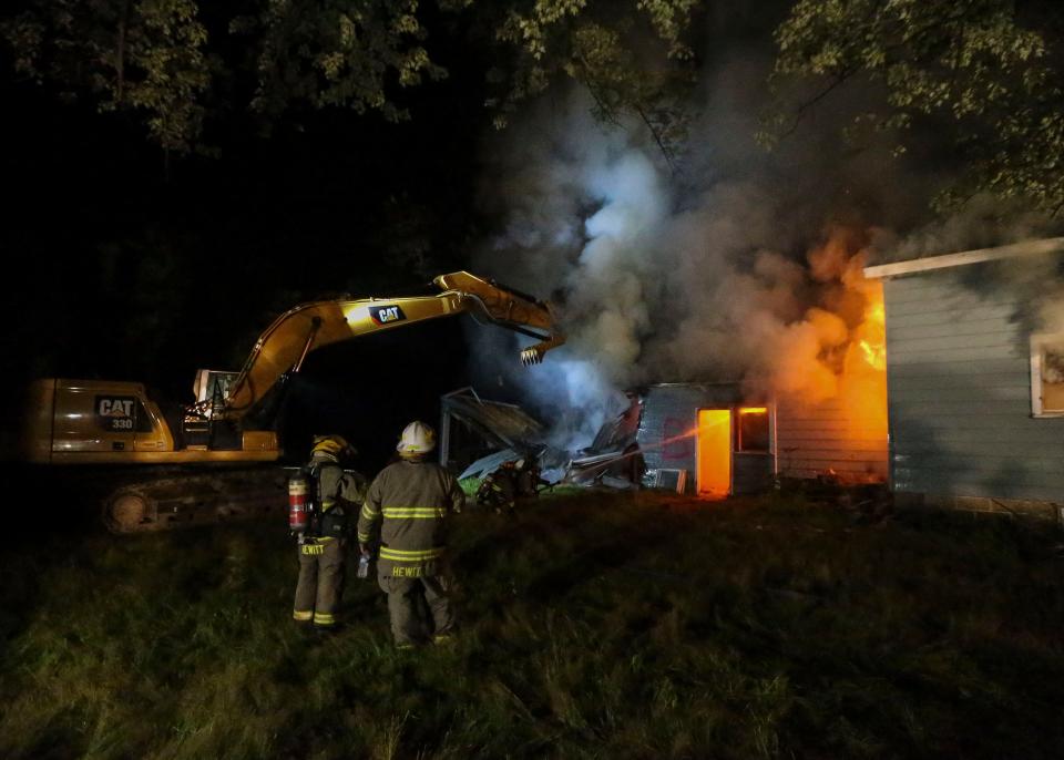 An excavator tears down a burning garage on Monday, August 1, 2022, at 4470 Neitzel Rd near Wisconsin Rapids, Wis. Firefighters from eight departments around central Wisconsin came together to train for various house fire scenarios before demolishing the house in a controlled burn.Tork Mason/USA TODAY NETWORK-Wisconsin 