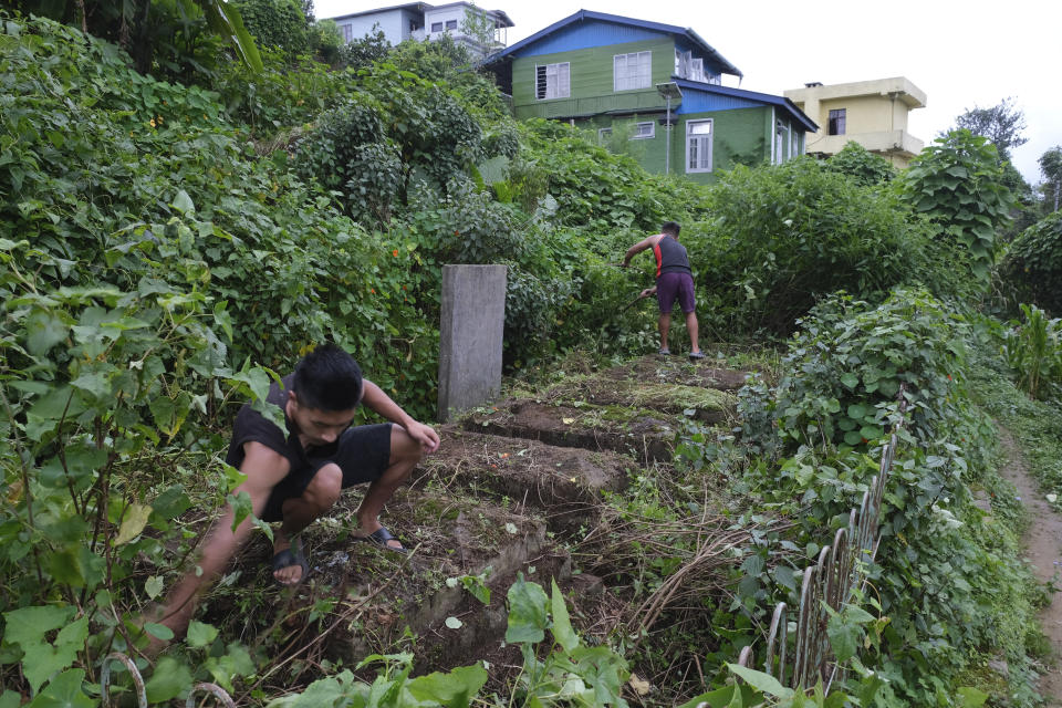 Angami Naga boys clear weed from the graves of 8 children, killed in 1976 when a World War II-era bomb exploded while they were playing, in Kohima village, the site of a bloody battle between the Japanese and British Commonwealth forces, in the northeastern Indian state of Nagaland, Tuesday, Aug. 18, 2020. For the fiercely independent Nagas, World War II was a conflict brought to their quiet lands by outsiders, and along with it, immeasurable loss. Wartime arms and ammunition are still being found in the region as reminders of the devastation. (AP Photo/Yirmiyan Arthur)