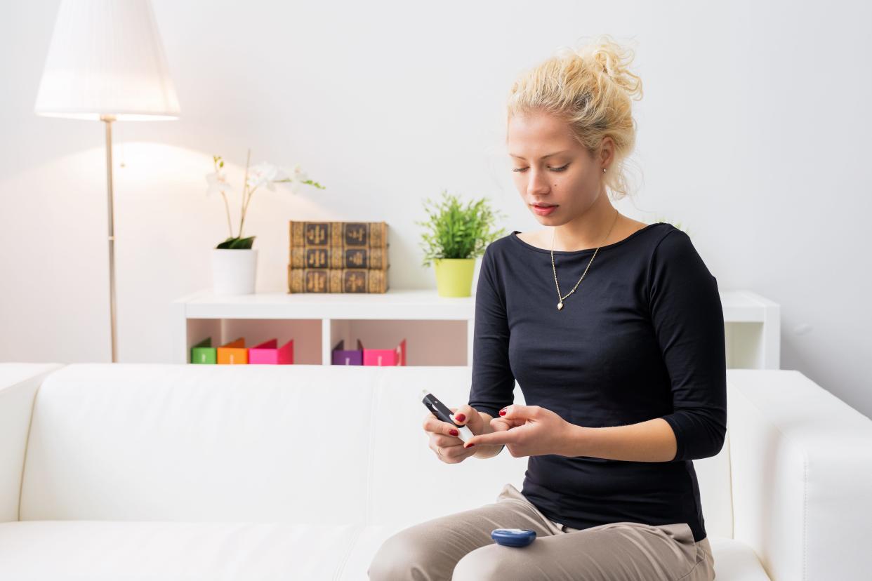 Woman sitting on couch and using diabetes needle