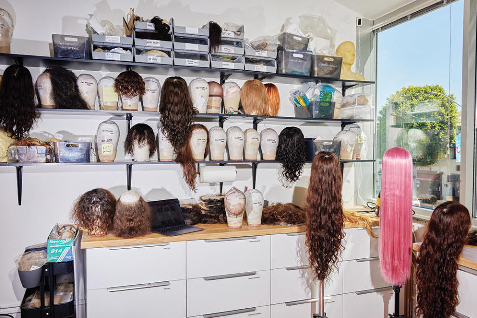 Wigs line shelves at the atelier.