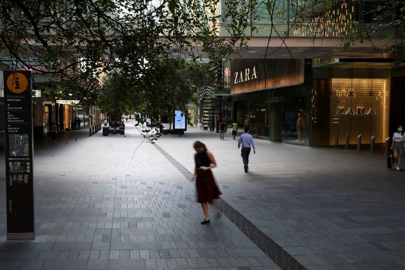 FILE PHOTO: People walk by an almost empty comercial area during a workday following the implementation of stricter social-distancing and self-isolation rules to limit the spread of the coronavirus disease (COVID-19) in Sydney