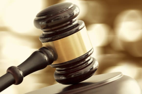 A brown gavel on top of a block of wood in a courtroom