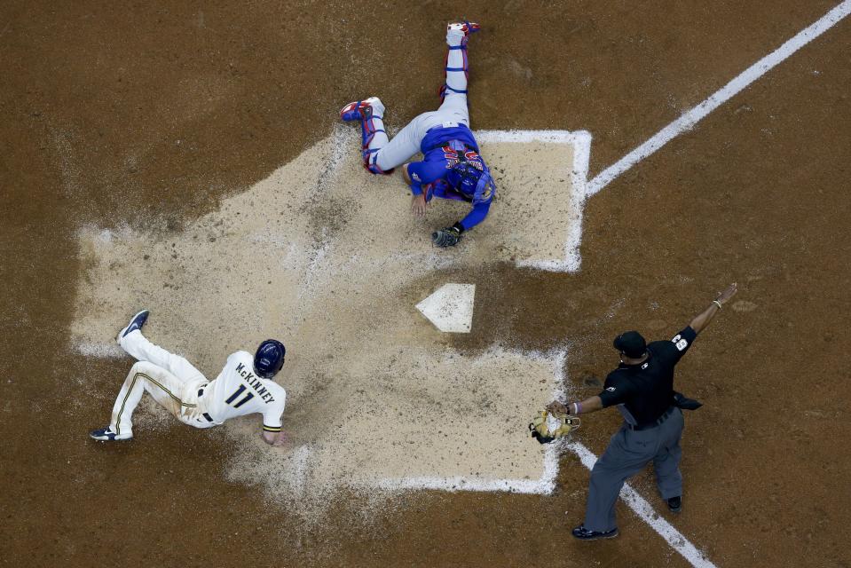 Milwaukee Brewers' Billy McKinney slides safely past Chicago Cubs catcher Austin Romine during the sixth inning of a baseball game Wednesday, April 14, 2021, in Milwaukee. McKinney scored from second on a hit by Corbin Burnes. (AP Photo/Morry Gash)