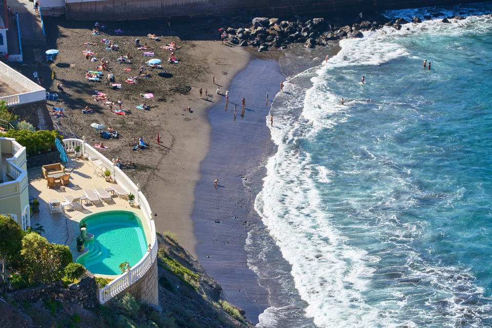 People sit on the Puerto de los Gigantes beach on Tenerife, Canary Islands