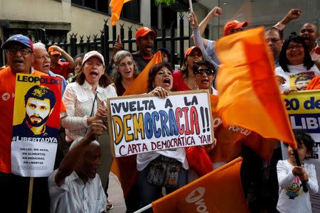 Opposition supporters holding a placard that reads "Back to the democracy. Democratic charter now", shout during a gathering outside the Organization of American States (OAS) headquarters in Caracas, Venezuela June 23, 2016. REUTERS/Mariana Bazo