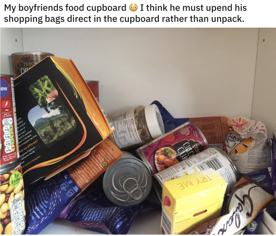 A cupboard with cans, boxes, and other food packages on their sides