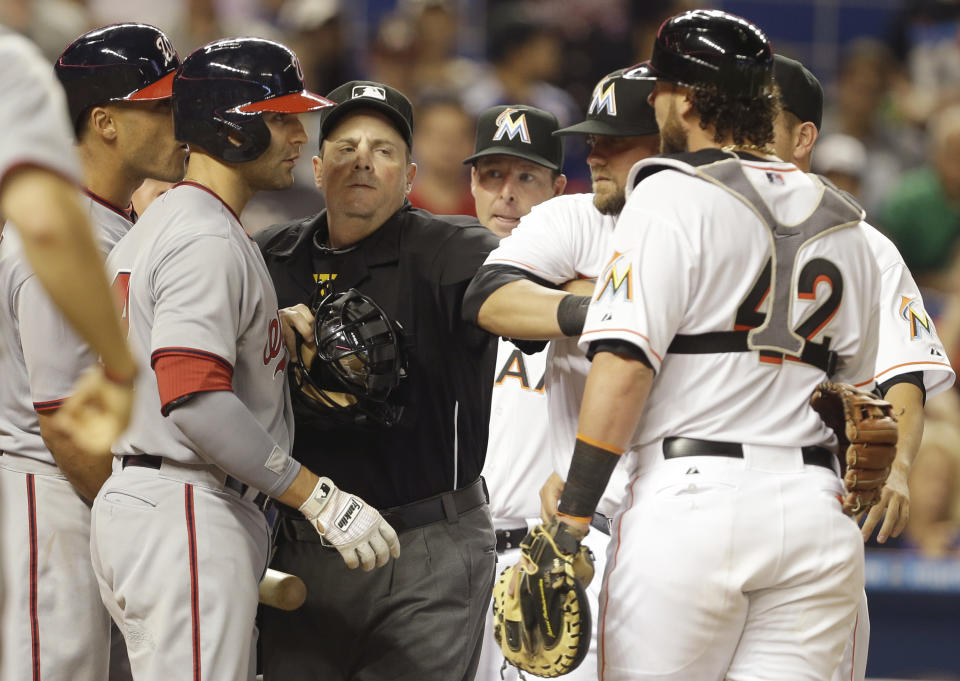 Home plate umpire Marty Foster, center, separates Washington Nationals' Ian Desmond, left, from Miami Marlins catcher Jarrod Saltalamacchia, right, during the fourth inning of the MLB National League baseball game, Tuesday, April 15, 2014, in Miami. Desmond had words with Saltalamacchia after the Miami Marlins starting pitcher Tom Koehler threw a close pitch. (AP Photo/Lynne Sladky)