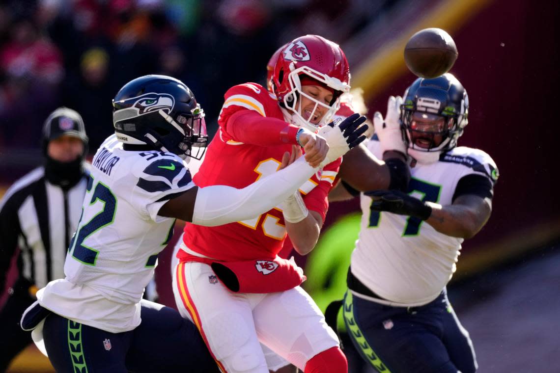 Kansas City Chiefs quarterback Patrick Mahomes is hit as he throws by Seattle Seahawks defensive end Darrell Taylor (52) during the first half of an NFL football game Saturday, Dec. 24, 2022, in Kansas City, Mo. (AP Photo/Charlie Riedel)