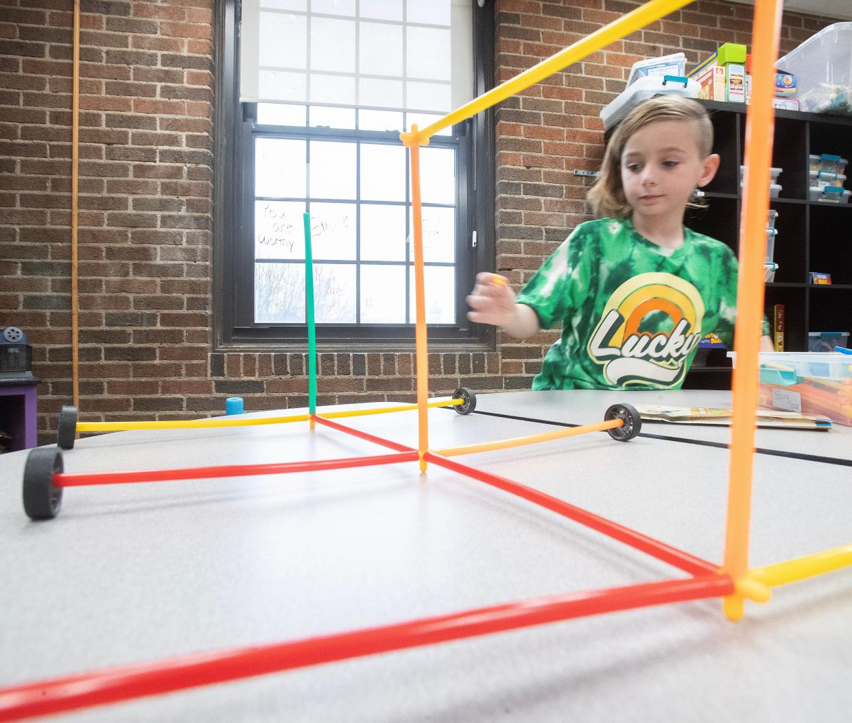 Eight-year-old Theo Bash builds a multi-wheeled vehicle out of Stem Straw building blocks at the Massillon YMCA School Day Off Kid Care program.