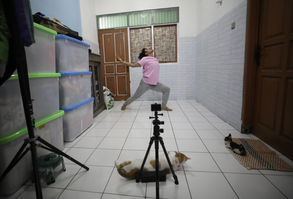 Dancer Siko Setyanto performs a dance while recording it using an action camera mounted on a tripod at his one-bedroom rented house in Jakarta, Indonesia Thursday, May 14, 2020. Two Indonesian choreographers are helping fellow dancers who lost their jobs due to the new coronavirus outbreak in the country by setting up a YouTube channel as a platform where dancers, choreographers and dance teachers can perform, then receive donation from viewers. (AP Photo/Dita Alangkara)