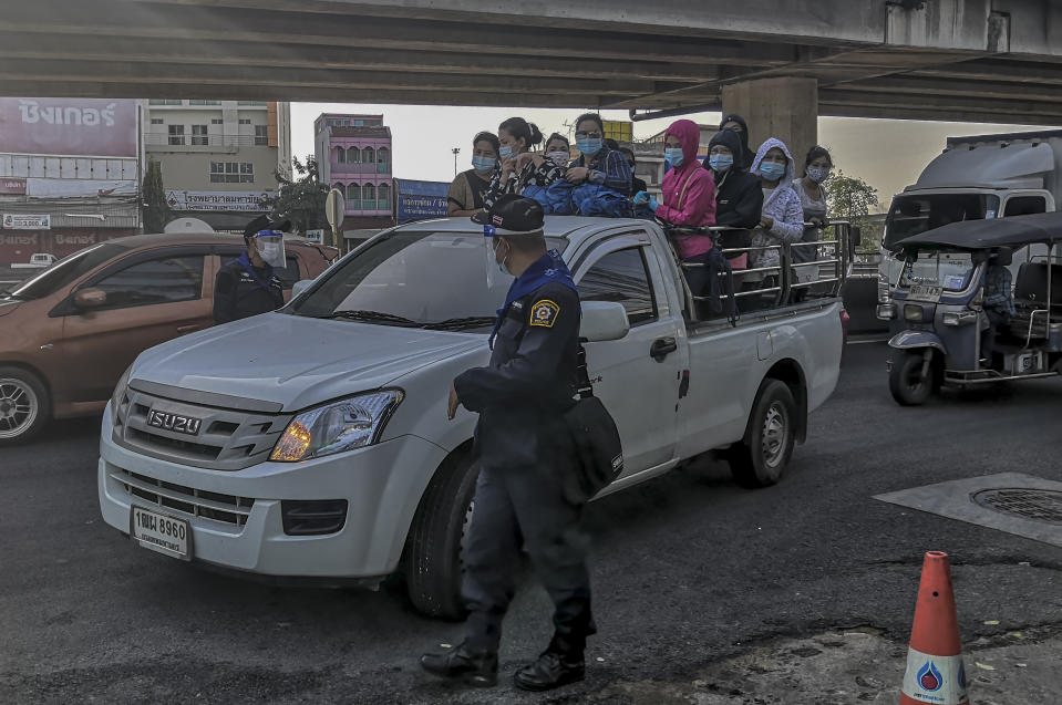 A group of migrant workers arrive in a back of a truck to get screened for COVID-19 in Samut Sakhon, South of Bangkok, Thailand, Sunday, Dec. 20, 2020. Thailand reported more than 500 new coronavirus cases on Saturday, the highest daily tally in a country that had largely brought the pandemic under control. (AP Photo/ Chalida Ekvitthayavechnukul)