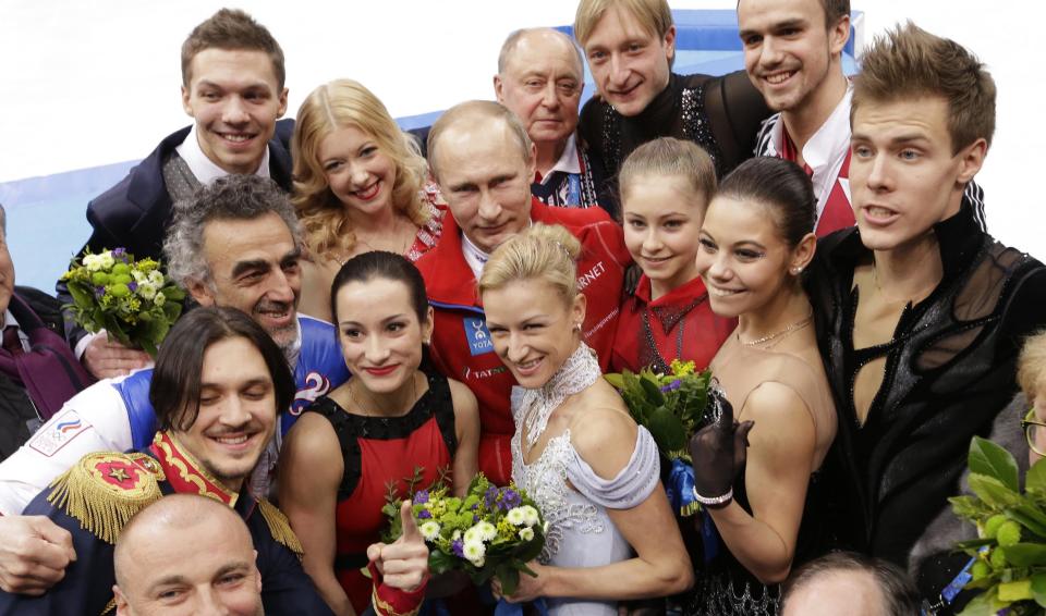 Russian President Vladimir Putin, centre back, poses for a photograph with the Russian team after they placed first in the team figure skating competition at the Iceberg Skating Palace during the 2014 Winter Olympics, Sunday, Feb. 9, 2014, in Sochi, Russia. (AP Photo/David J. Phillip )