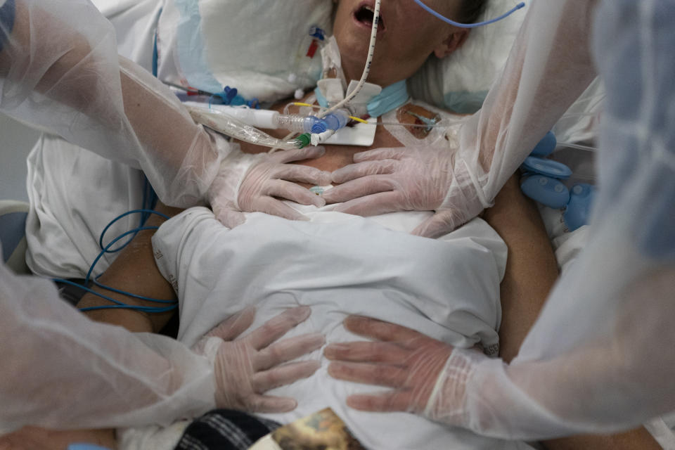 Nurses perform timed breathing exercises on a COVID-19 patient on a ventilator in the COVID-19 intensive care unit at the la Timone hospital in Marseille, southern France, Friday, Dec. 31, 2021. Paris region health authorities have instructed hospitals to cancel more non-urgent medical procedures to free up intensive-care beds for the growing influx of people gravely sick with COVID-19. (AP Photo/Daniel Cole)