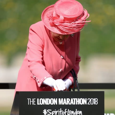 The Queen has pressed the start button and is wearing a bright coral outfit - Credit: WPA Pool/Getty Images