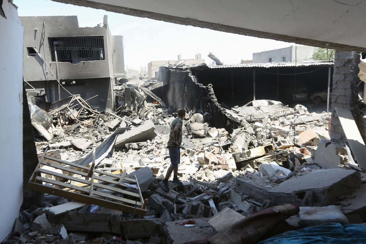 A fighter loyal to the Libyan Government of National Accord (GNA) forces checks a building near the the Yarmouk military compound, south of the Libyan capital Tripoli following air strikes: AFP/Getty Images