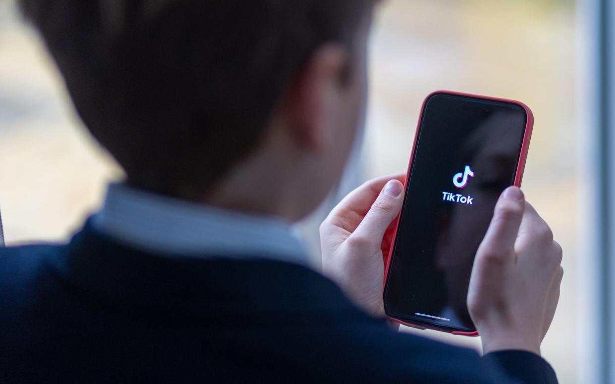 12-year-old school boy looks at a iPhone screen showing the social media app TikTok