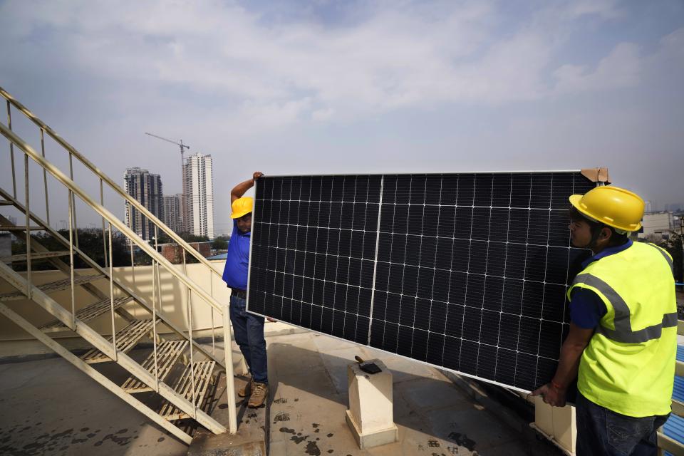 Workers of Solar Square carry a panel on the rooftop of a residence in Gurugram on the outskirts of New Delhi, India, Tuesday, Feb. 20, 2024. India is renewing its push to add rooftop solar to meet the needs of a fast-growing nation that's hungry for energy. (AP Photo/Manish Swarup)