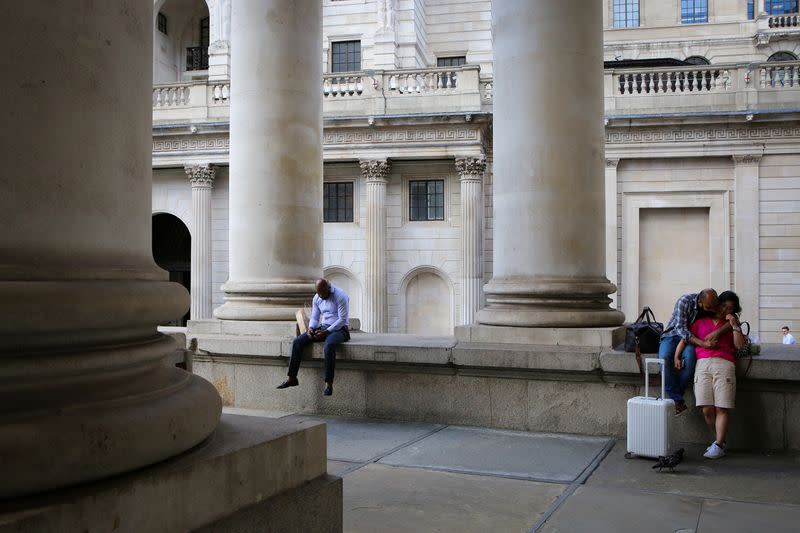 People relax in front of the Bank of England in London's financial district