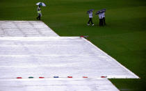 Cricket - Australia v South Africa - Second Test cricket match - Bellerive Oval, Hobart, Australia - 13/11/16 A security guard accompanies umpires Richard Kettleborough, Aleem Dar and Mick Martell as they hold umbrellas while inspecting the covered pitch as rain falls during the second day of the second test between Australia and South Africa. REUTERS/David Gray