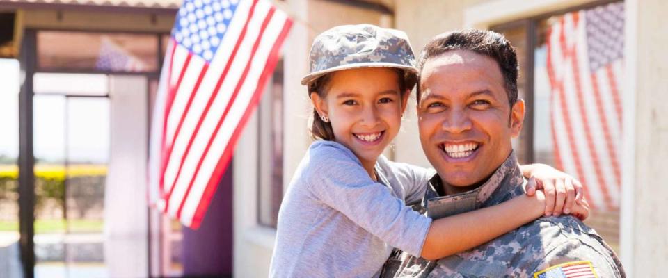 portrait of us army soldier and little daughter outside their home