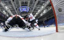 Canada's Tara Watchorn scores on Switzerland's goalie Florence Schelling while Switzerland's Julia Marty (R) defends during the first period of their women's ice hockey game at the 2014 Sochi Winter Olympics, February 8, 2014. REUTERS/Matt Slocum/Pool (RUSSIA - Tags: SPORT OLYMPICS SPORT ICE HOCKEY)