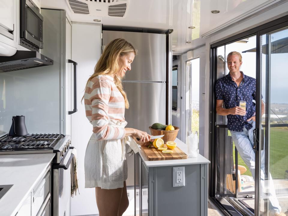 a person in the kitchen and another standing by the glass door