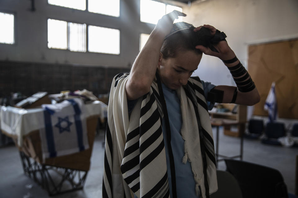 A Jewish student places his tefillin on his head during morning prayer in the synagogue of the Maoz Military Preparation Program after it was damaged by fire during overnight clashes in the mixed Jewish-Arab city of Lod, Israel, Friday, May 14, 2021. (AP Photo/Heidi Levine)