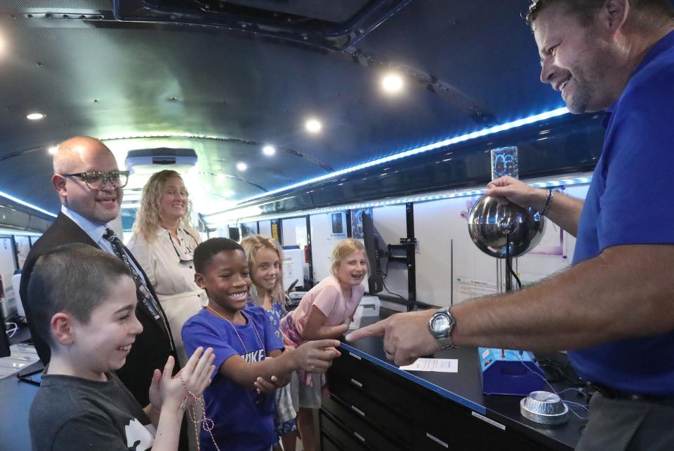 Beachside Elementary student Dae'Shawn Smith reacts as he waits for a spark off the finger of STEM bus resource teacher David Van Slyke, who is touching the dome of the Van De Graff Generator, Tuesday, Oct. 3, 2023, during a tour of Volusia County Schools, new STEM bus.