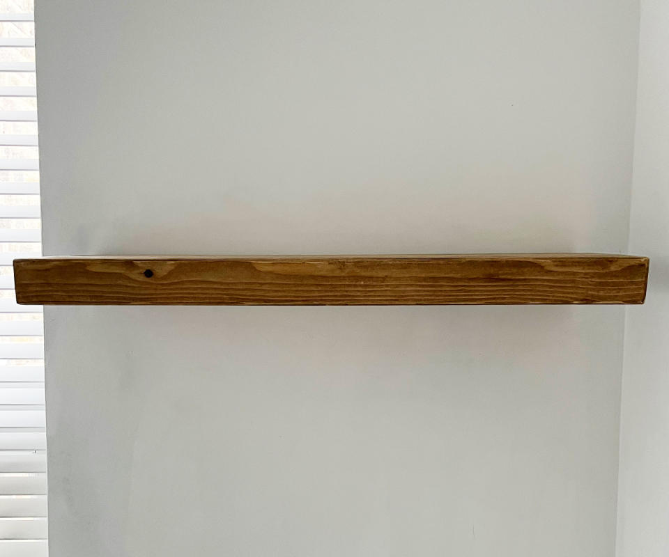 Wooden floating shelf on a white wall in a corridor
