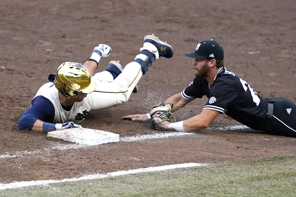 Notre Dame's Brooks Coetzee (42) safely tags first base as Mississippi State's Luke Hancock (20) dives towards him after retrieving a passed ball during the NCAA college baseball super regional game, Sunday, June 13, 2021, in Starkville, Miss. (AP Photo/Rogelio V. Solis)