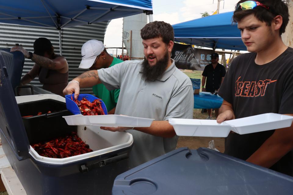 Joshua Moore and Jonathan Guillen fill up trays of crawfish to be served at the Amarillo Crawfish Festival at the Starlight Ranch Event Center Saturday.