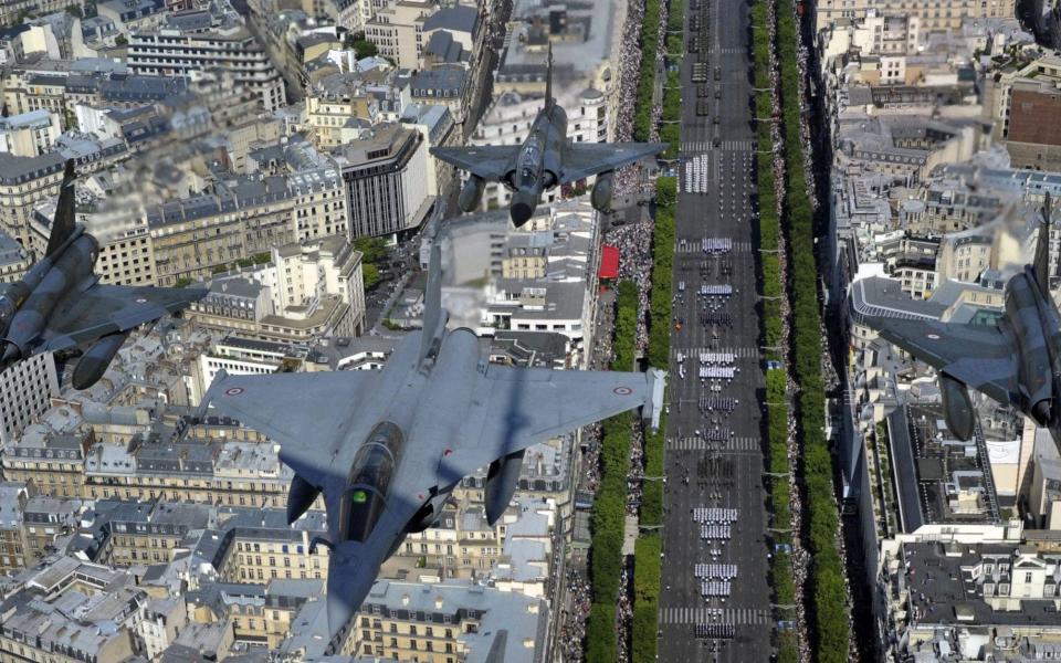 A Rafale jet flies and three Mirage 2000-N jets fly over the Arc de Triomphe in Paris on Bastille Day 2011