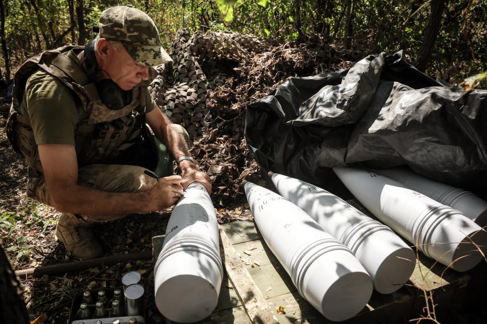 A Ukrainian soldier signs 152mm artillery shells ready to fire at Russian positions in Donetsk (24th Mechanized Brigade of Ukrai)