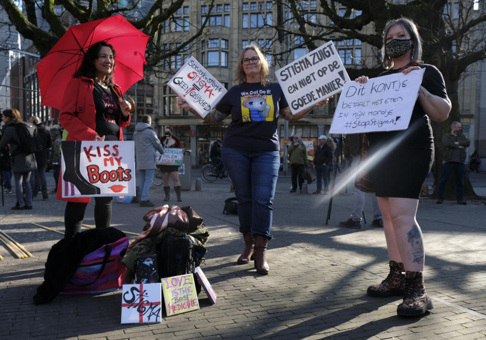 Sex workers carry signs protesting unequal treatment and stigmatizing during a demonstration in The Hague, Netherlands, Tuesday, March 2, 2021. Stores in one village opened briefly, cafe owners across the Netherlands were putting tables and chairs on their outdoor terraces and sex workers demonstrated outside parliament in protests against the government's tough coronavirus lockdown. (AP Photo/Patrick Post)