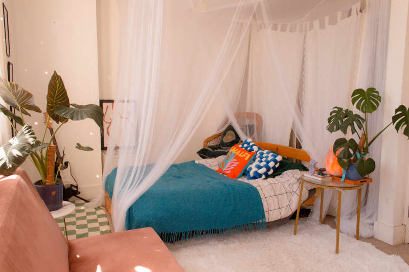 Decorative pillows on a bed with a canopy near a shag rug.