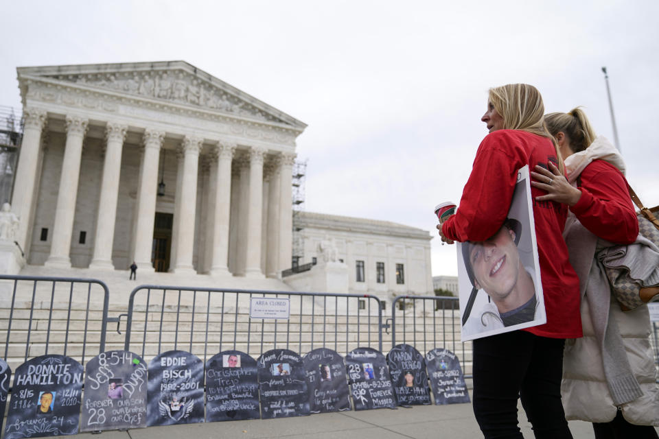 FILE - Jen Trejo holds a photo of her son Christopher as she is comforted outside the Supreme Court where signs in the shape of grave headstones, with information on people who died from using OxyContin, line a security fence, Monday, Dec. 4, 2023, in Washington. The Supreme Court on Thursday, June 27, 2024, rejected a nationwide settlement with OxyContin maker Purdue Pharma that would have shielded members of the Sackler family who own the company from civil lawsuits over the toll of opioids but also would have provided billions of dollars to combat the opioid epidemic. (AP Photo/Stephanie Scarbrough, File)