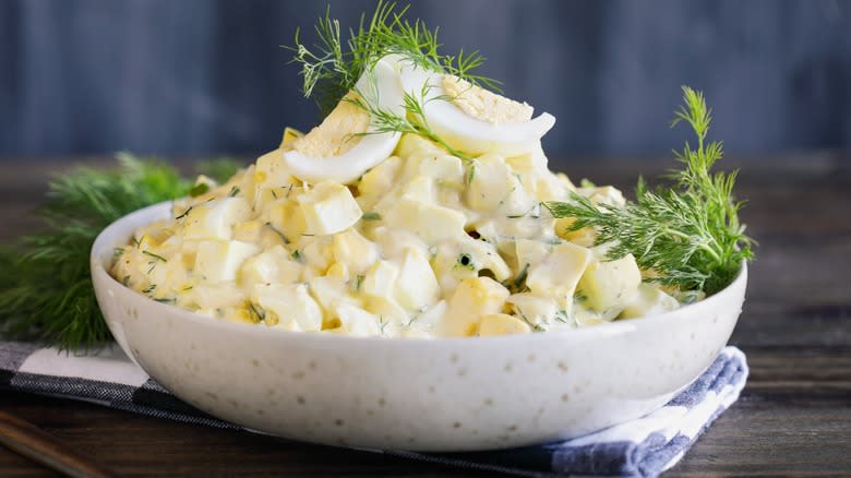 A bowl of egg salad garnished with fresh dill