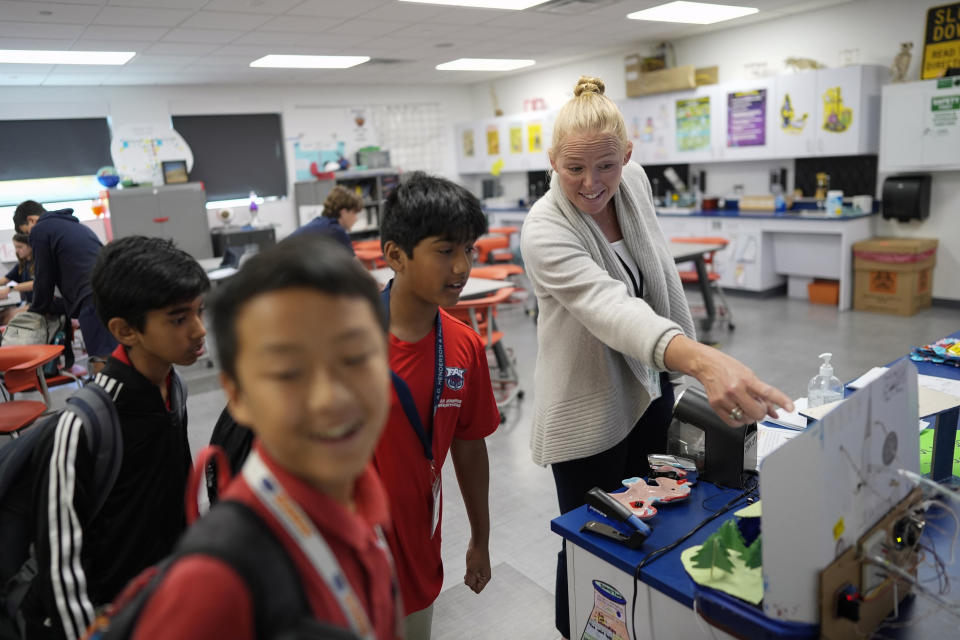 Middle school science teacher Vanessa Stevenson, right, talks with students in her Science Fair class at A.D. Henderson School in Boca Raton, Fla., Tuesday, April 16, 2024. When teachers at the K-8 public school, one of the top-performing schools in Florida, are asked how they succeed, one answer is universal: They have autonomy. (AP Photo/Rebecca Blackwell)