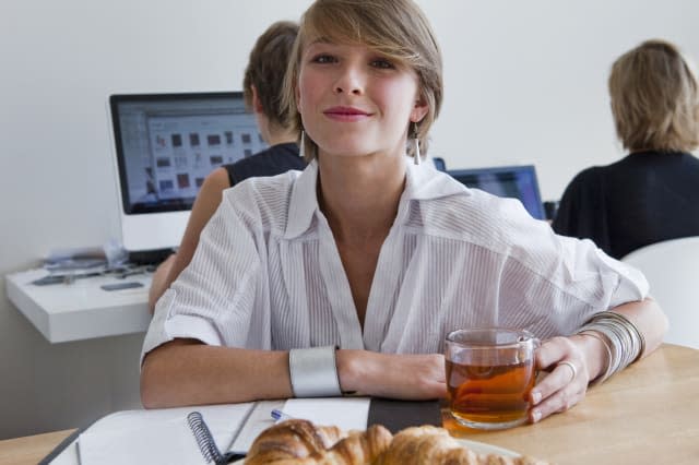 Young woman in the office drinking tea